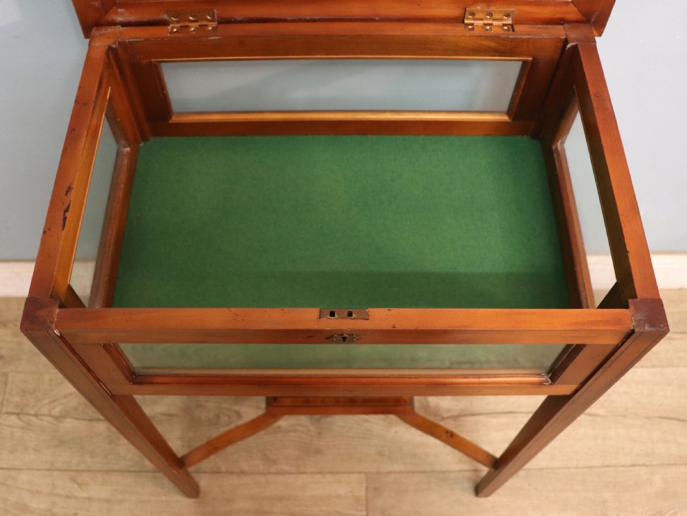 A glazed yew wood bijouterie display table featuring a green velvet interior lining, lower undertier, and Breitling 1884 logo printed on the top glass. View XIX