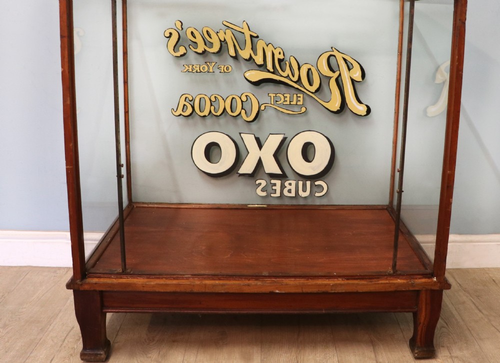 A glazed hardwood countertop display cabinet with sign-written lettering for Rowntrees Elect Cocoa and OXO Cubes on the front glass panel. View VI