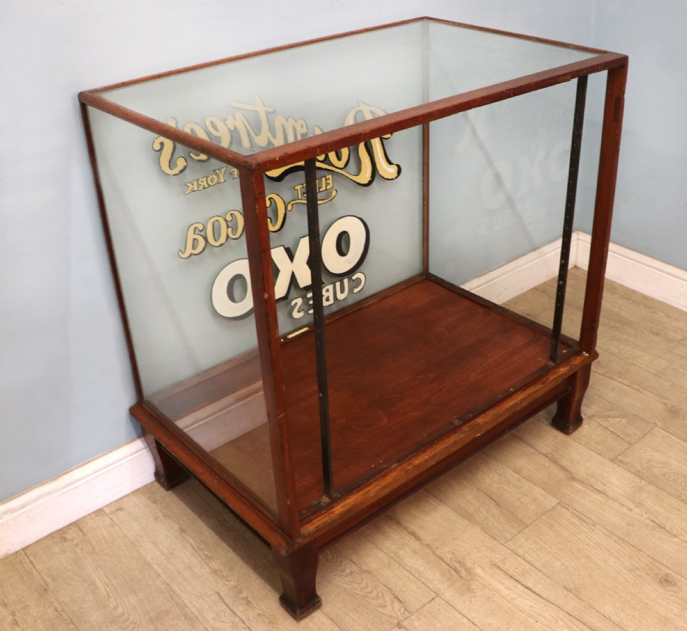 A glazed hardwood countertop display cabinet with sign-written lettering for Rowntrees Elect Cocoa and OXO Cubes on the front glass panel. View VII