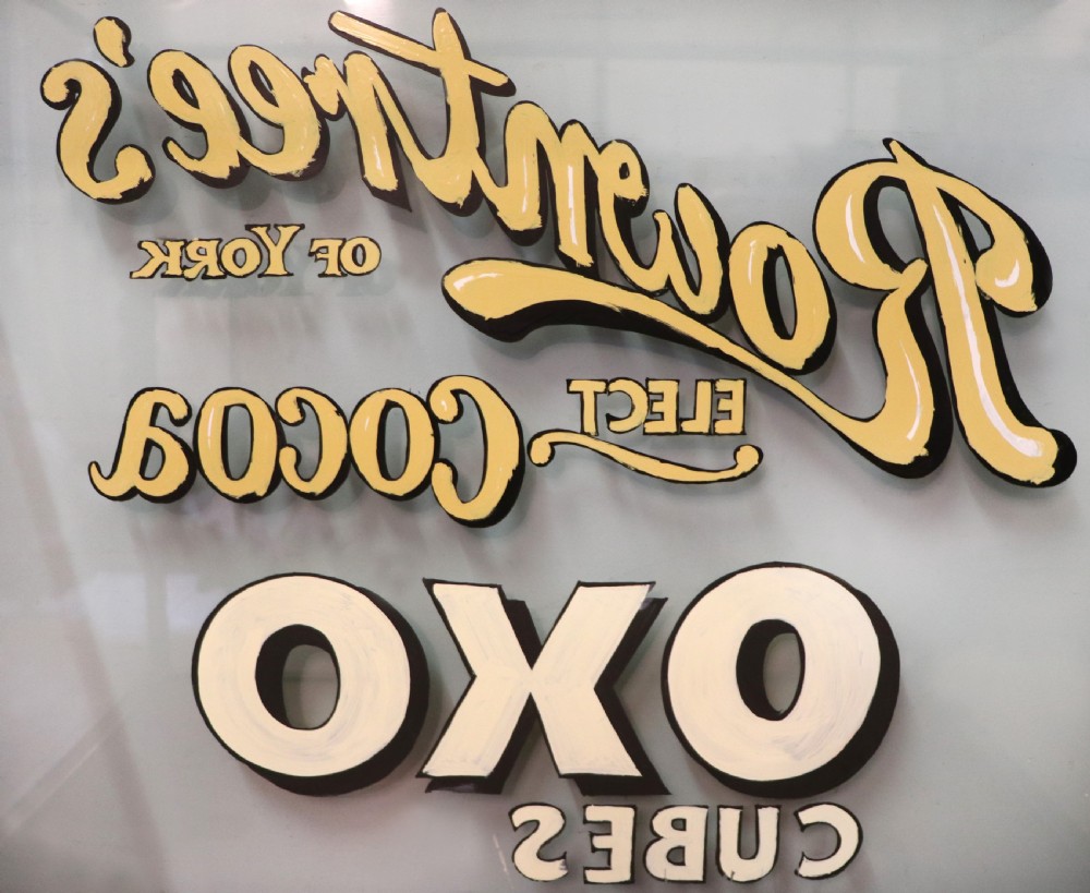 A glazed hardwood countertop display cabinet with sign-written lettering for Rowntrees Elect Cocoa and OXO Cubes on the front glass panel. View XV