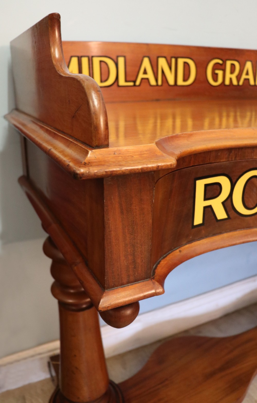 A Victorian mahogany console table with turned legs, a low gallery back, and yellow painted lettering reading Midland Grand Hotel Room 101. View VI