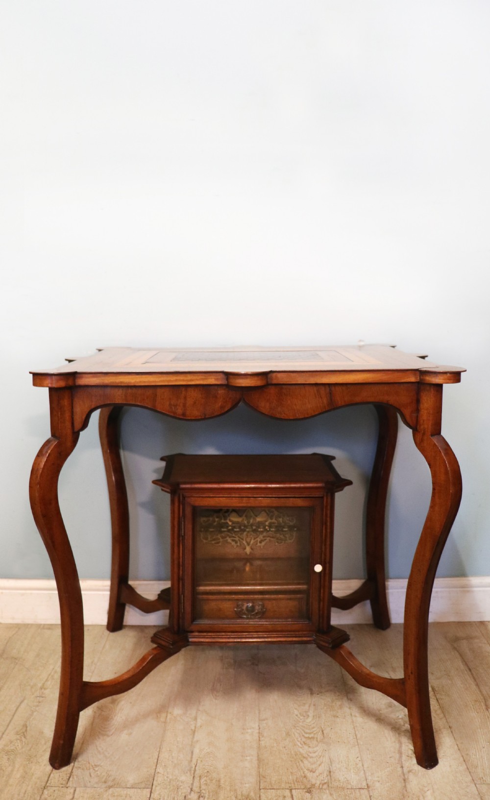A late Victorian wooden occasional table featuring a geometric parquetry inlaid top, slender cabriole legs, and a lower glazed smokers cabinet. View II