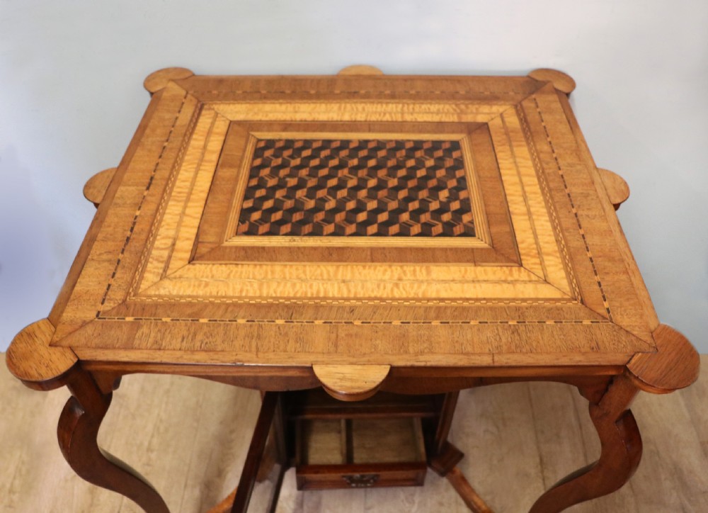 A late Victorian wooden occasional table featuring a geometric parquetry inlaid top, slender cabriole legs, and a lower glazed smokers cabinet. View V