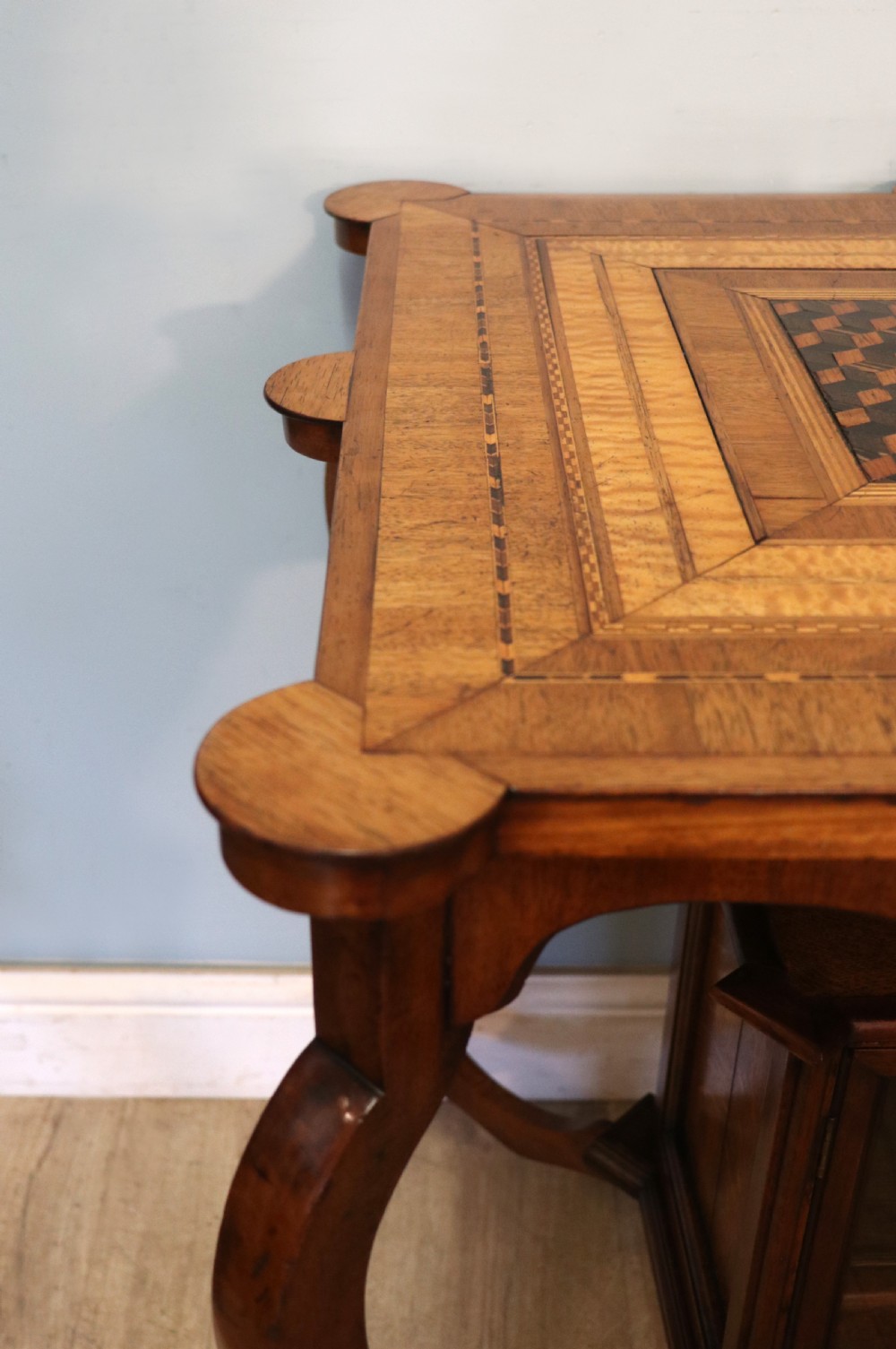 A late Victorian wooden occasional table featuring a geometric parquetry inlaid top, slender cabriole legs, and a lower glazed smokers cabinet. View X