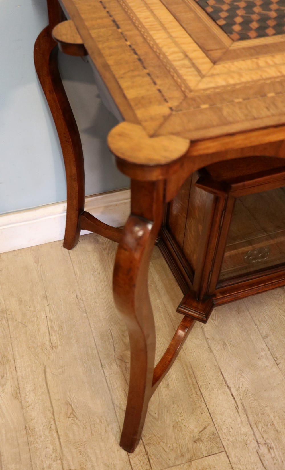 A late Victorian wooden occasional table featuring a geometric parquetry inlaid top, slender cabriole legs, and a lower glazed smokers cabinet. View XII