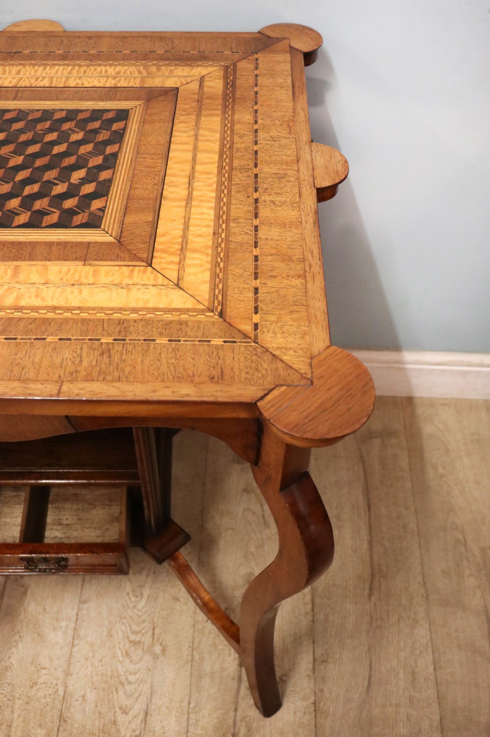 A late Victorian wooden occasional table featuring a geometric parquetry inlaid top, slender cabriole legs, and a lower glazed smokers cabinet. View XVI