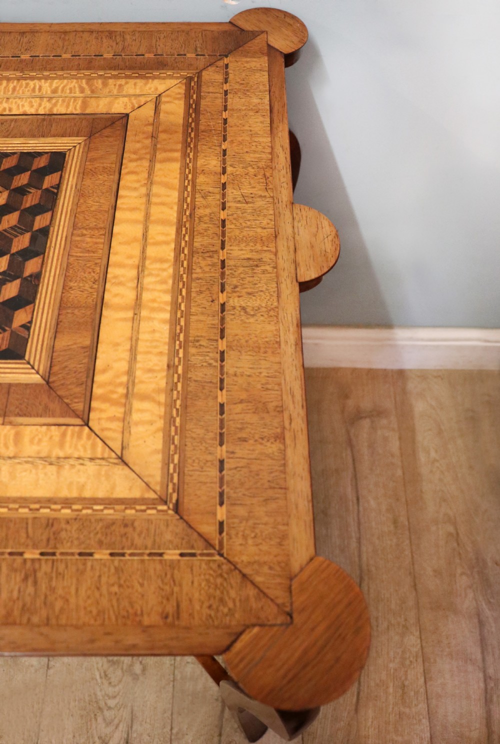 A late Victorian wooden occasional table featuring a geometric parquetry inlaid top, slender cabriole legs, and a lower glazed smokers cabinet. View XVII