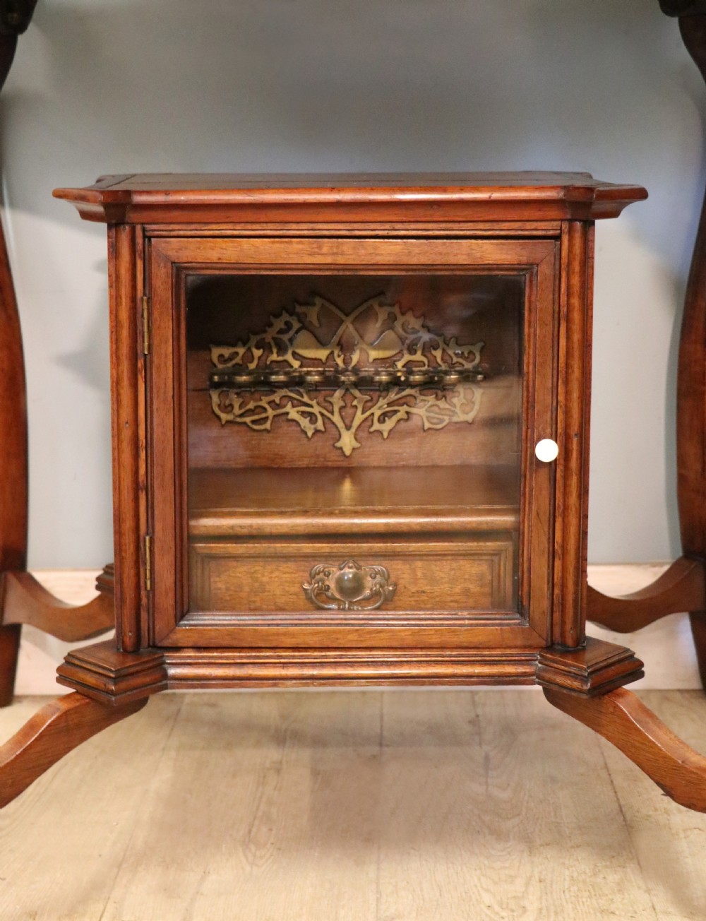 A late Victorian wooden occasional table featuring a geometric parquetry inlaid top, slender cabriole legs, and a lower glazed smokers cabinet. View XX