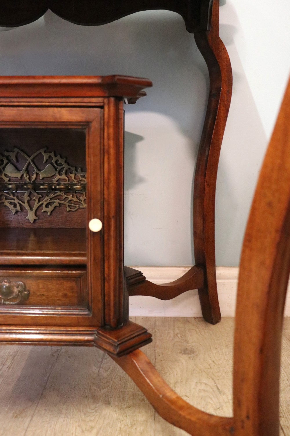 A late Victorian wooden occasional table featuring a geometric parquetry inlaid top, slender cabriole legs, and a lower glazed smokers cabinet. View XXVII