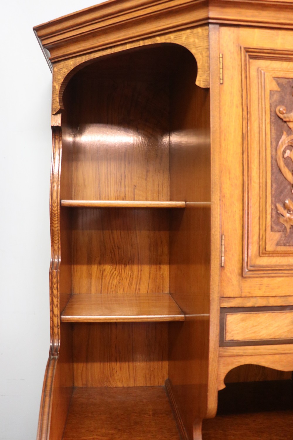 A late nineteenth-century American walnut compendium wardrobe featuring a full-length mirrored door, carved timber motif panel, open side shelving, brass handles, and integrated drawers. View IV
