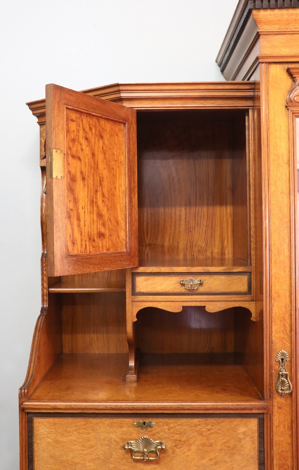 A late nineteenth-century American walnut compendium wardrobe featuring a full-length mirrored door, carved timber motif panel, open side shelving, brass handles, and integrated drawers. View VIII