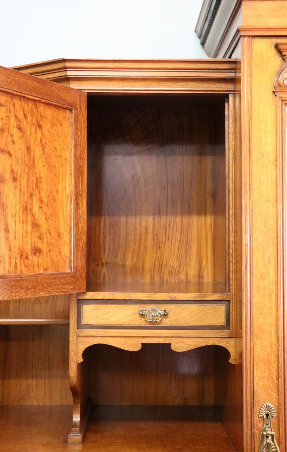 A late nineteenth-century American walnut compendium wardrobe featuring a full-length mirrored door, carved timber motif panel, open side shelving, brass handles, and integrated drawers. View IX