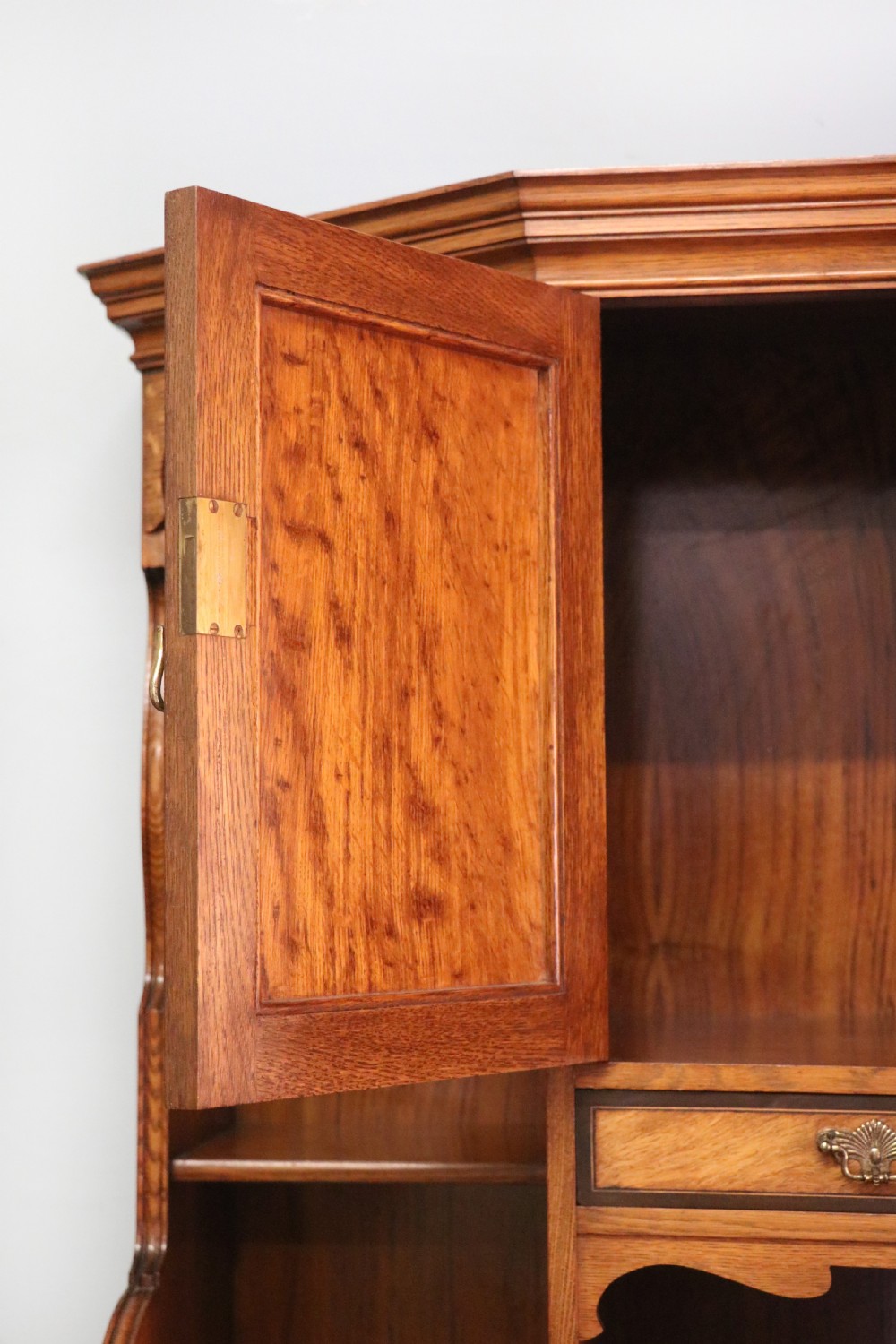 A late nineteenth-century American walnut compendium wardrobe featuring a full-length mirrored door, carved timber motif panel, open side shelving, brass handles, and integrated drawers. View X