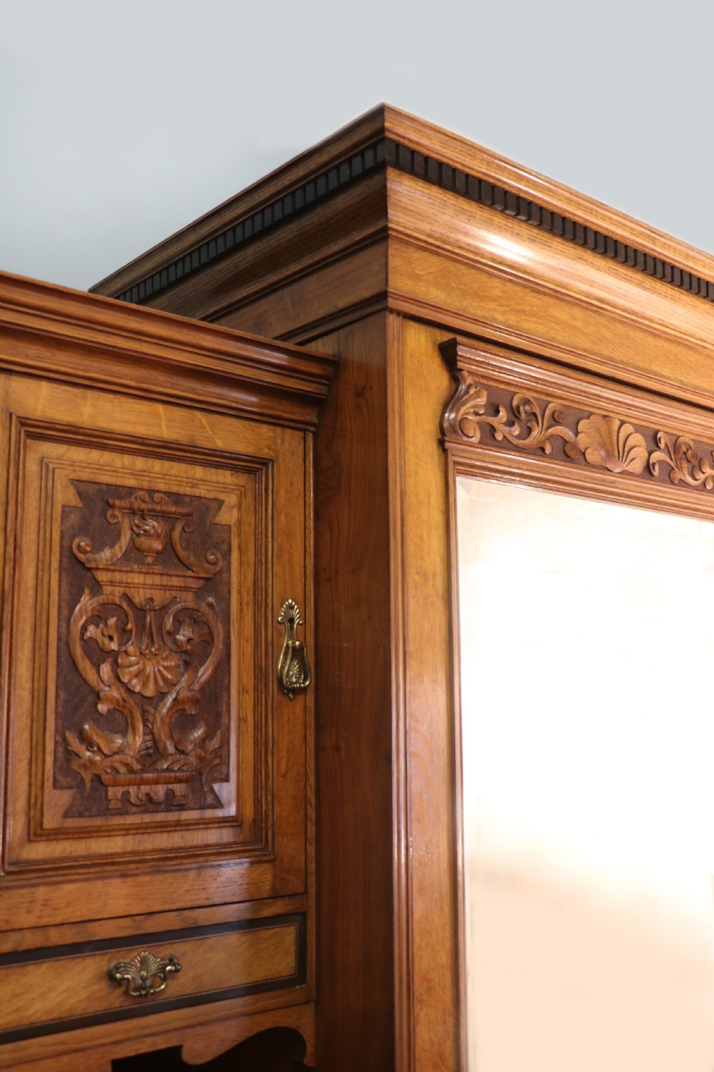 A late nineteenth-century American walnut compendium wardrobe featuring a full-length mirrored door, carved timber motif panel, open side shelving, brass handles, and integrated drawers. View XIV