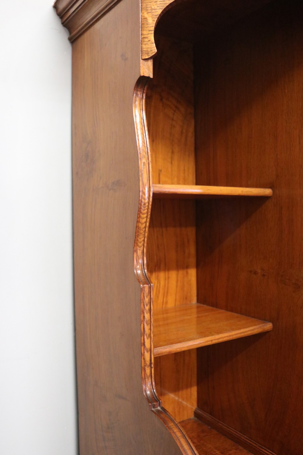 A late nineteenth-century American walnut compendium wardrobe featuring a full-length mirrored door, carved timber motif panel, open side shelving, brass handles, and integrated drawers. View XV