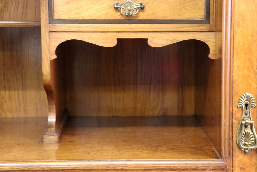 A late nineteenth-century American walnut compendium wardrobe featuring a full-length mirrored door, carved timber motif panel, open side shelving, brass handles, and integrated drawers. View XVI