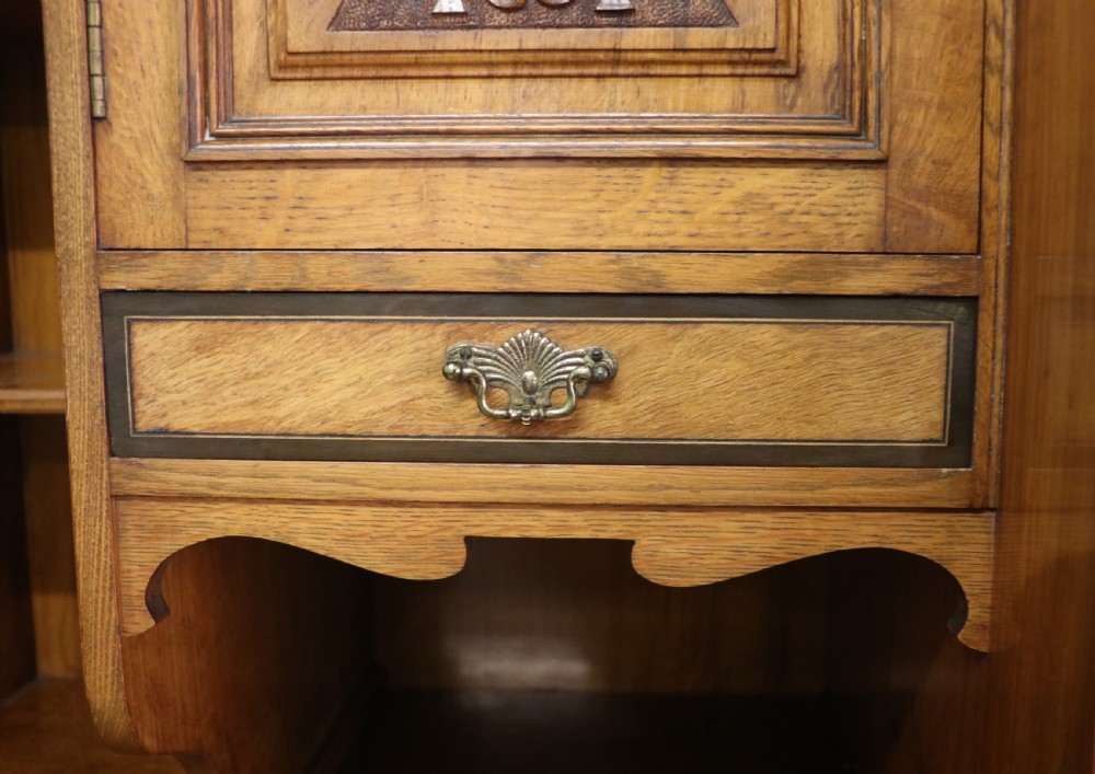 A late nineteenth-century American walnut compendium wardrobe featuring a full-length mirrored door, carved timber motif panel, open side shelving, brass handles, and integrated drawers. View XVII