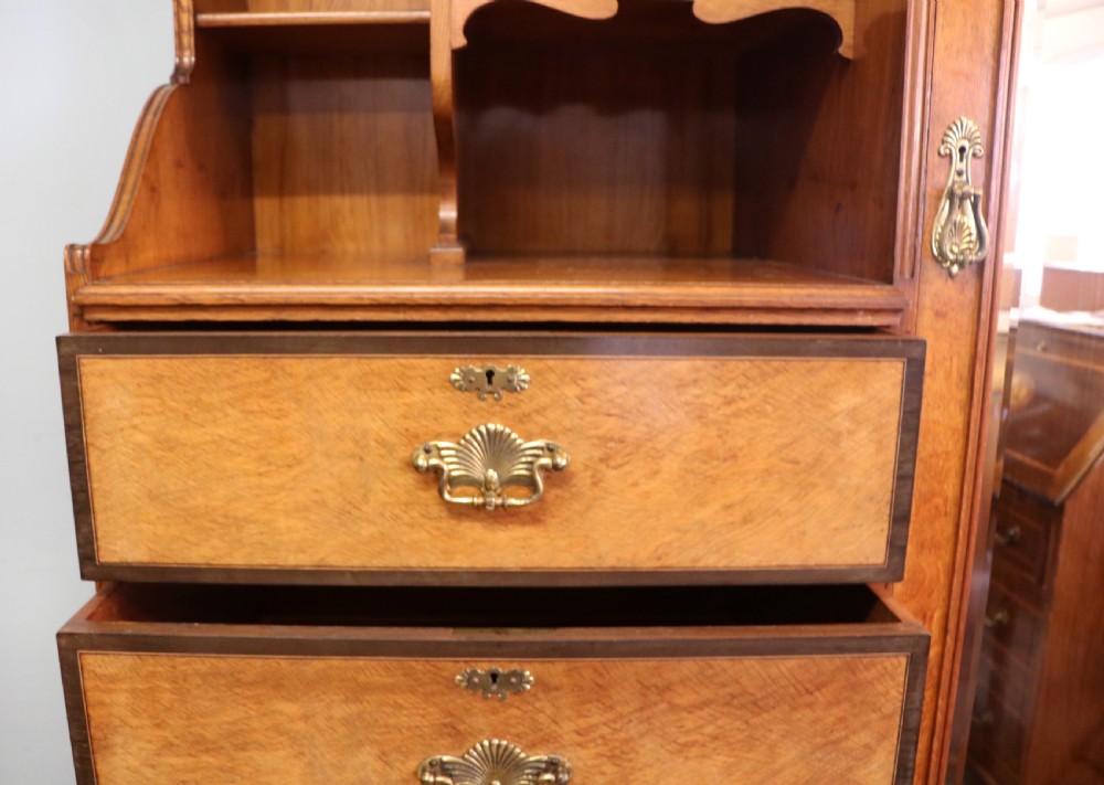 A late nineteenth-century American walnut compendium wardrobe featuring a full-length mirrored door, carved timber motif panel, open side shelving, brass handles, and integrated drawers. View XVIII