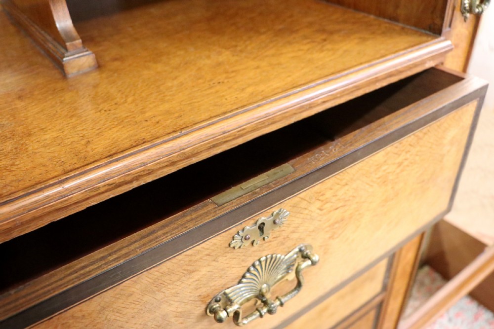A late nineteenth-century American walnut compendium wardrobe featuring a full-length mirrored door, carved timber motif panel, open side shelving, brass handles, and integrated drawers. View XXIII