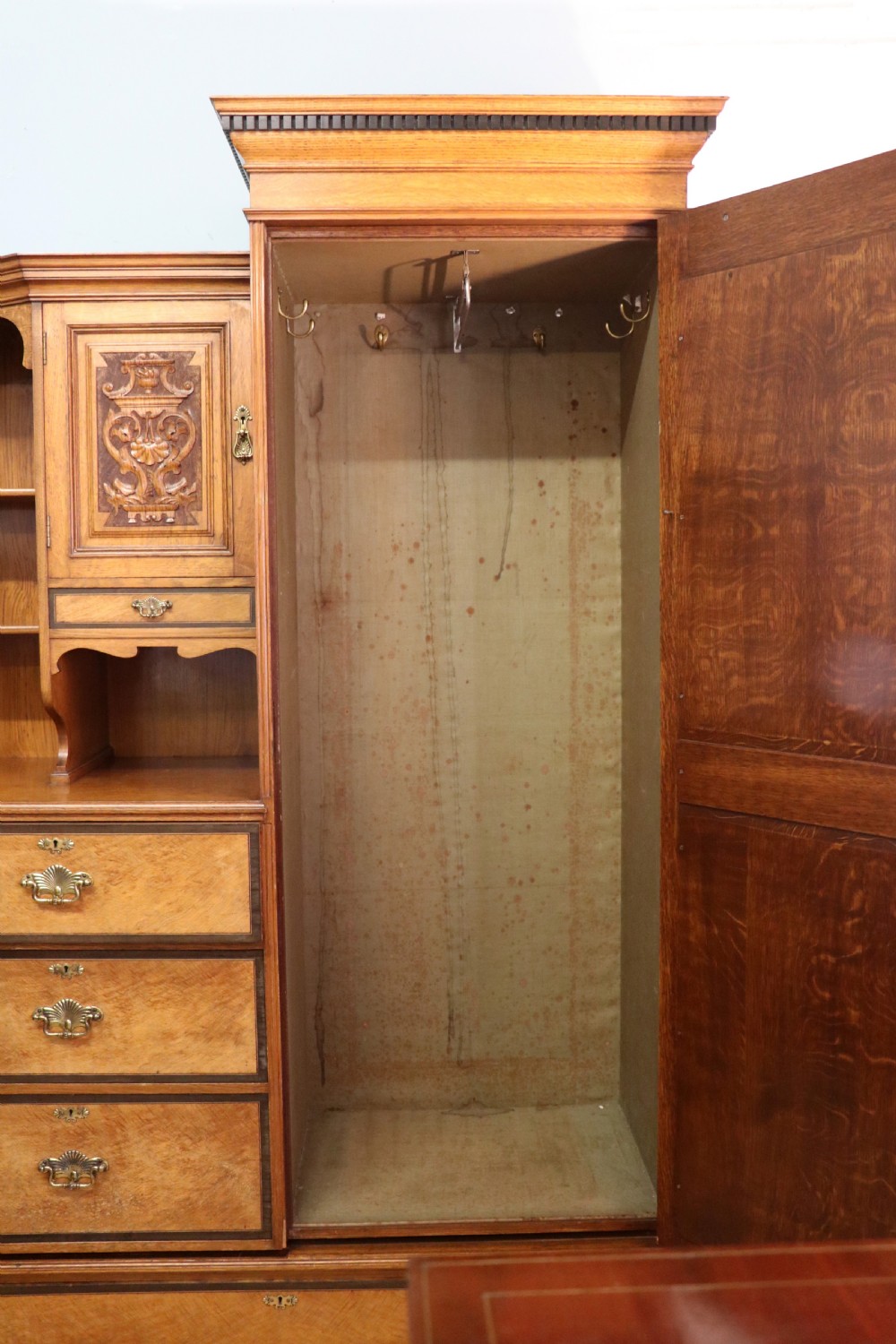 A late nineteenth-century American walnut compendium wardrobe featuring a full-length mirrored door, carved timber motif panel, open side shelving, brass handles, and integrated drawers. View XXIX