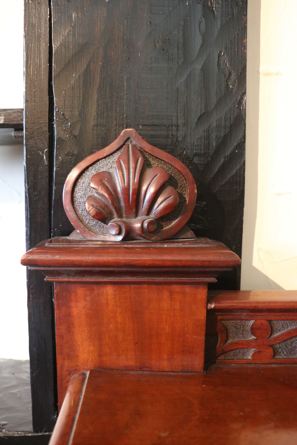 A Victorian mahogany three-tiered dumb waiter featuring carved decorative pediments, supporting brackets, lower drawers, and ceramic castors. View X