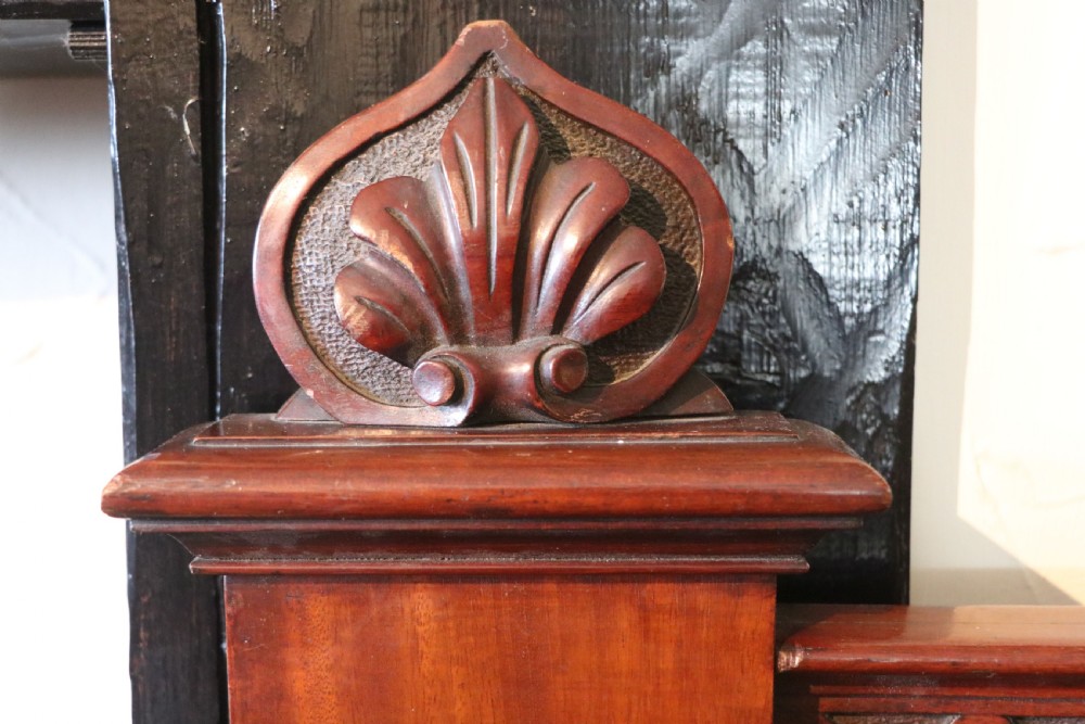 A Victorian mahogany three-tiered dumb waiter featuring carved decorative pediments, supporting brackets, lower drawers, and ceramic castors. View XI