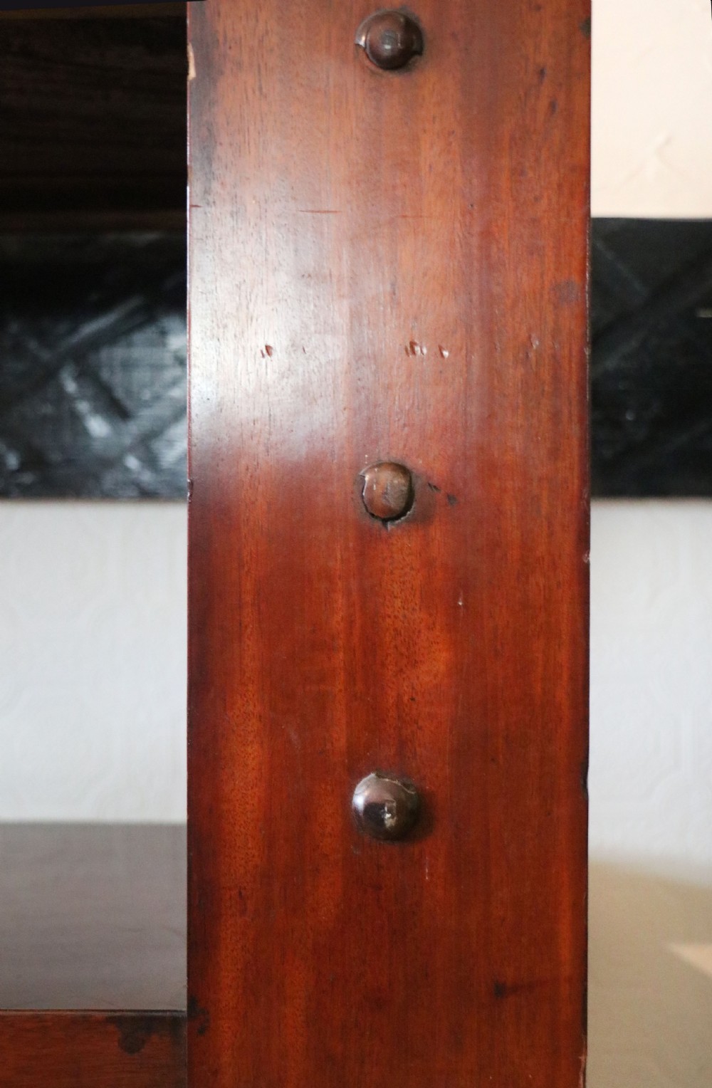 A Victorian mahogany three-tiered dumb waiter featuring carved decorative pediments, supporting brackets, lower drawers, and ceramic castors. View XVII