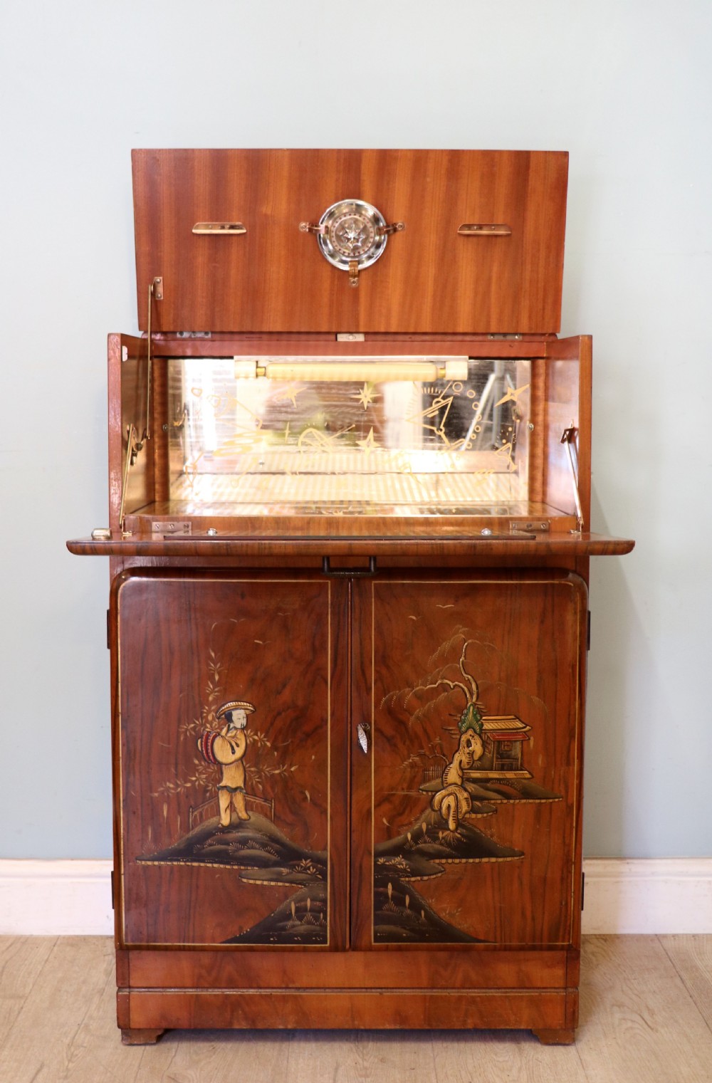 A wonderfully stylish piece of retro furniture An Art Deco walnut and chinoiserie-decorated cabinet by Rivington. 