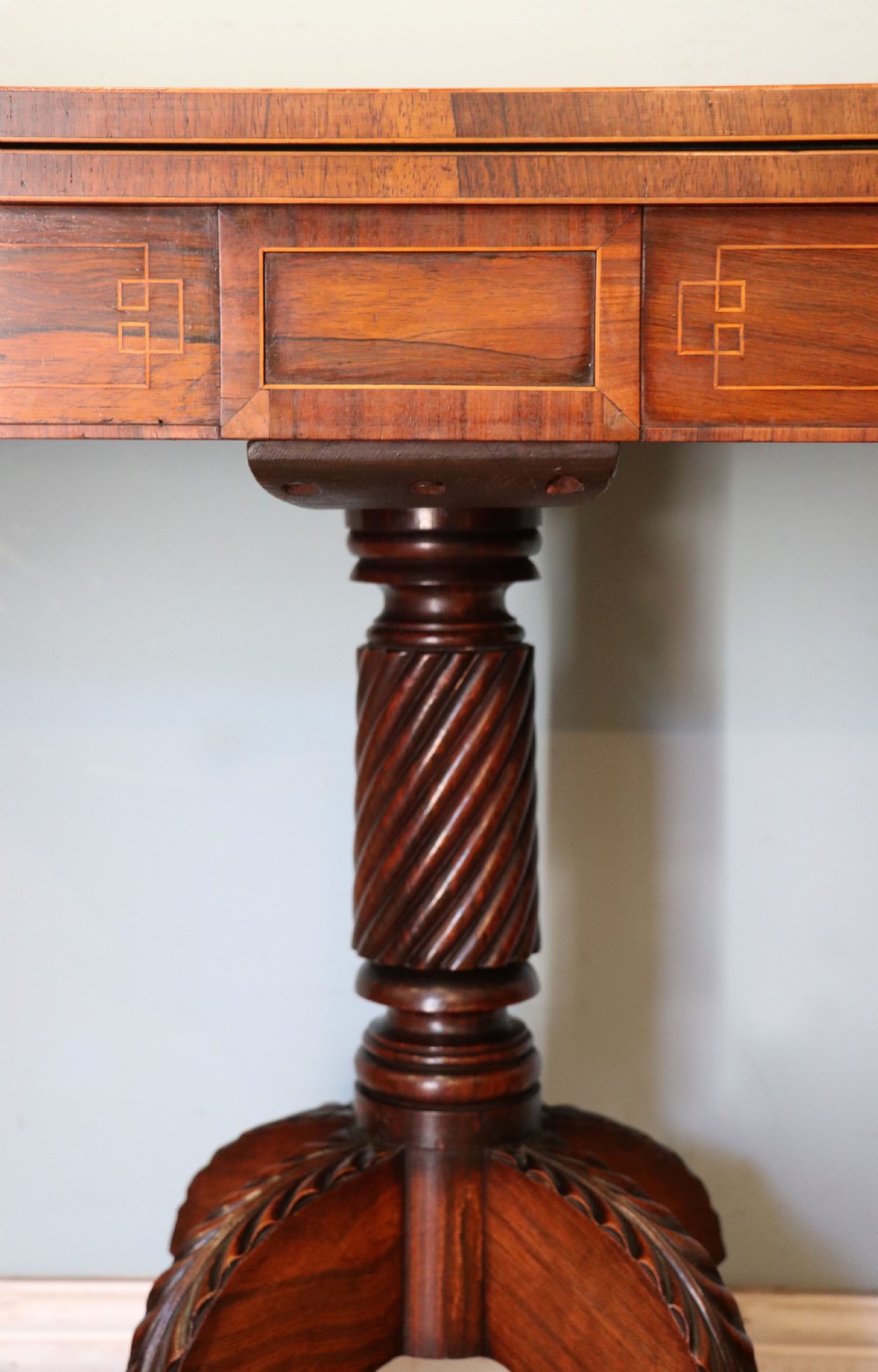 A late Georgian dark rosewood card table featuring an open fold-over green baize top supported on a spiral-carved pedestal and splayed legs with brass paw castors. View VIII
