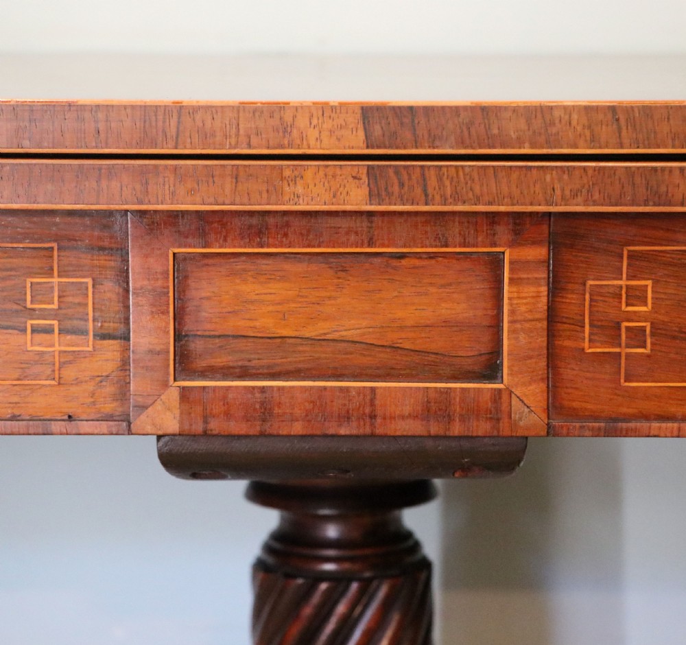 A late Georgian dark rosewood card table featuring an open fold-over green baize top supported on a spiral-carved pedestal and splayed legs with brass paw castors. View XII