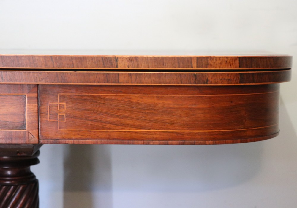 A late Georgian dark rosewood card table featuring an open fold-over green baize top supported on a spiral-carved pedestal and splayed legs with brass paw castors. View XIII