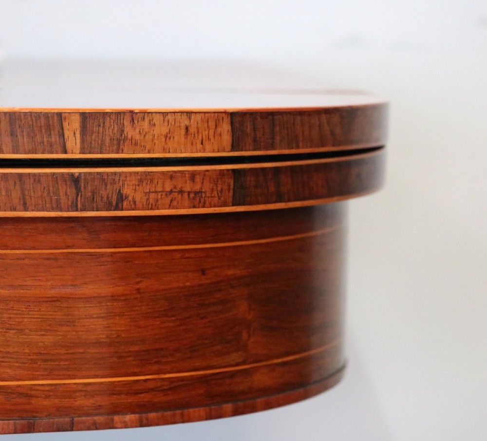 A late Georgian dark rosewood card table featuring an open fold-over green baize top supported on a spiral-carved pedestal and splayed legs with brass paw castors. View XIV