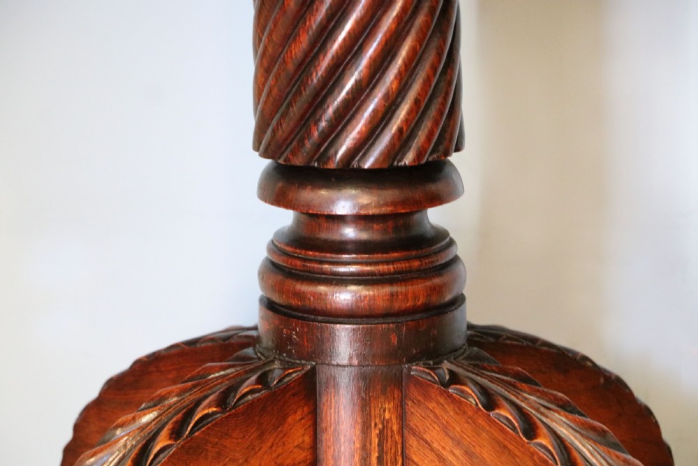 A late Georgian dark rosewood card table featuring an open fold-over green baize top supported on a spiral-carved pedestal and splayed legs with brass paw castors. View XVII