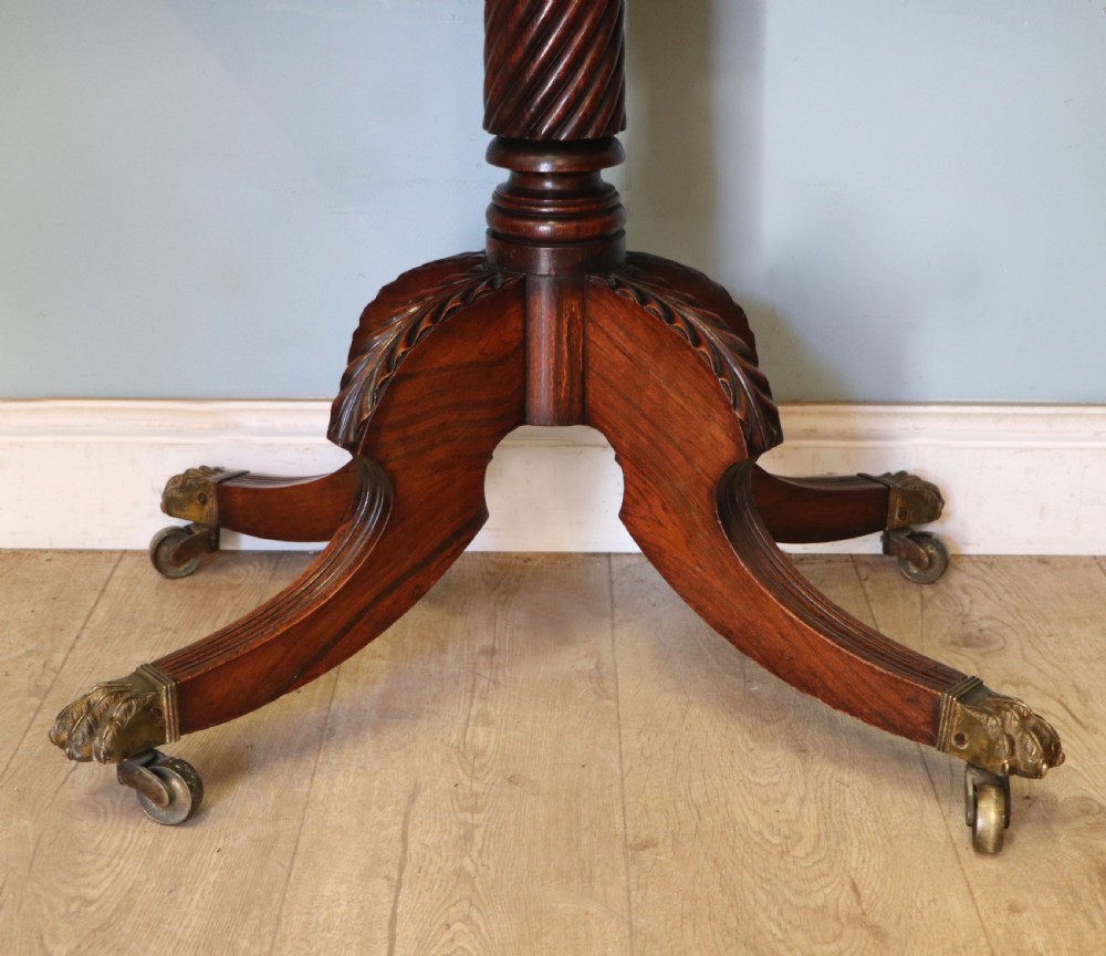 A late Georgian dark rosewood card table featuring an open fold-over green baize top supported on a spiral-carved pedestal and splayed legs with brass paw castors. View XVIII