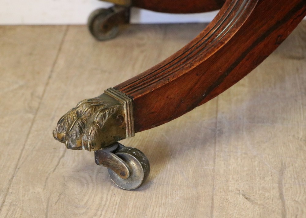 A late Georgian dark rosewood card table featuring an open fold-over green baize top supported on a spiral-carved pedestal and splayed legs with brass paw castors. View XX