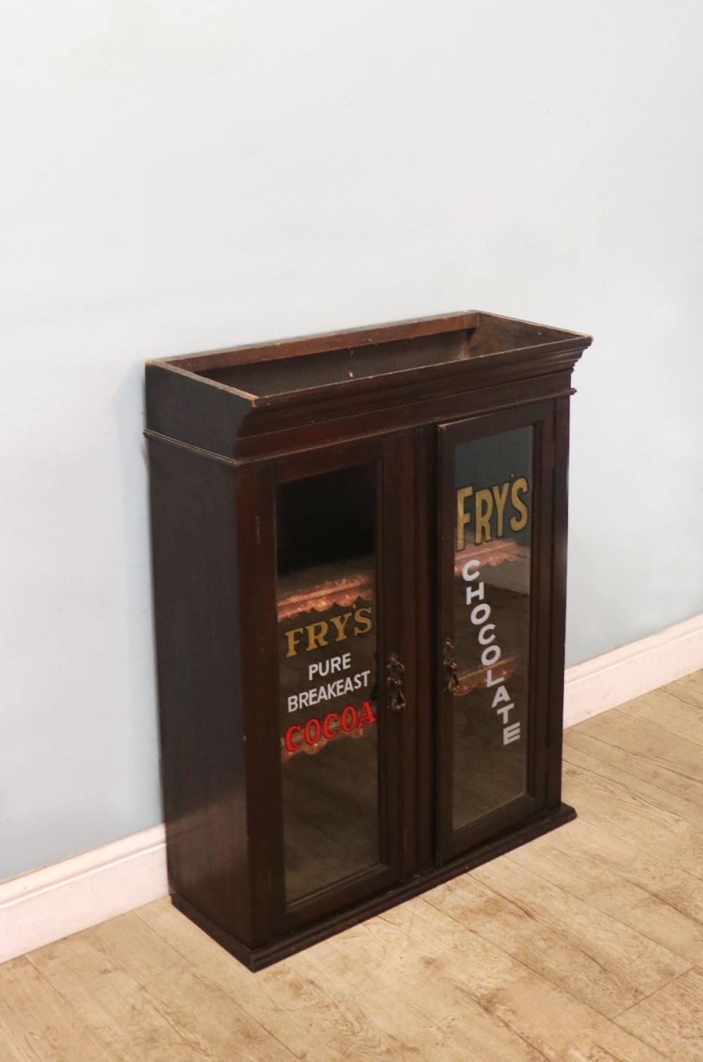 A dark mahogany Victorian display cabinet featuring glazed doors painted with Frys Cocoa and Chocolate advertising typography. View III