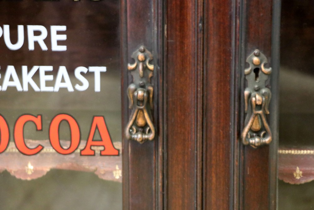 A dark mahogany Victorian display cabinet featuring glazed doors painted with Frys Cocoa and Chocolate advertising typography. View VII