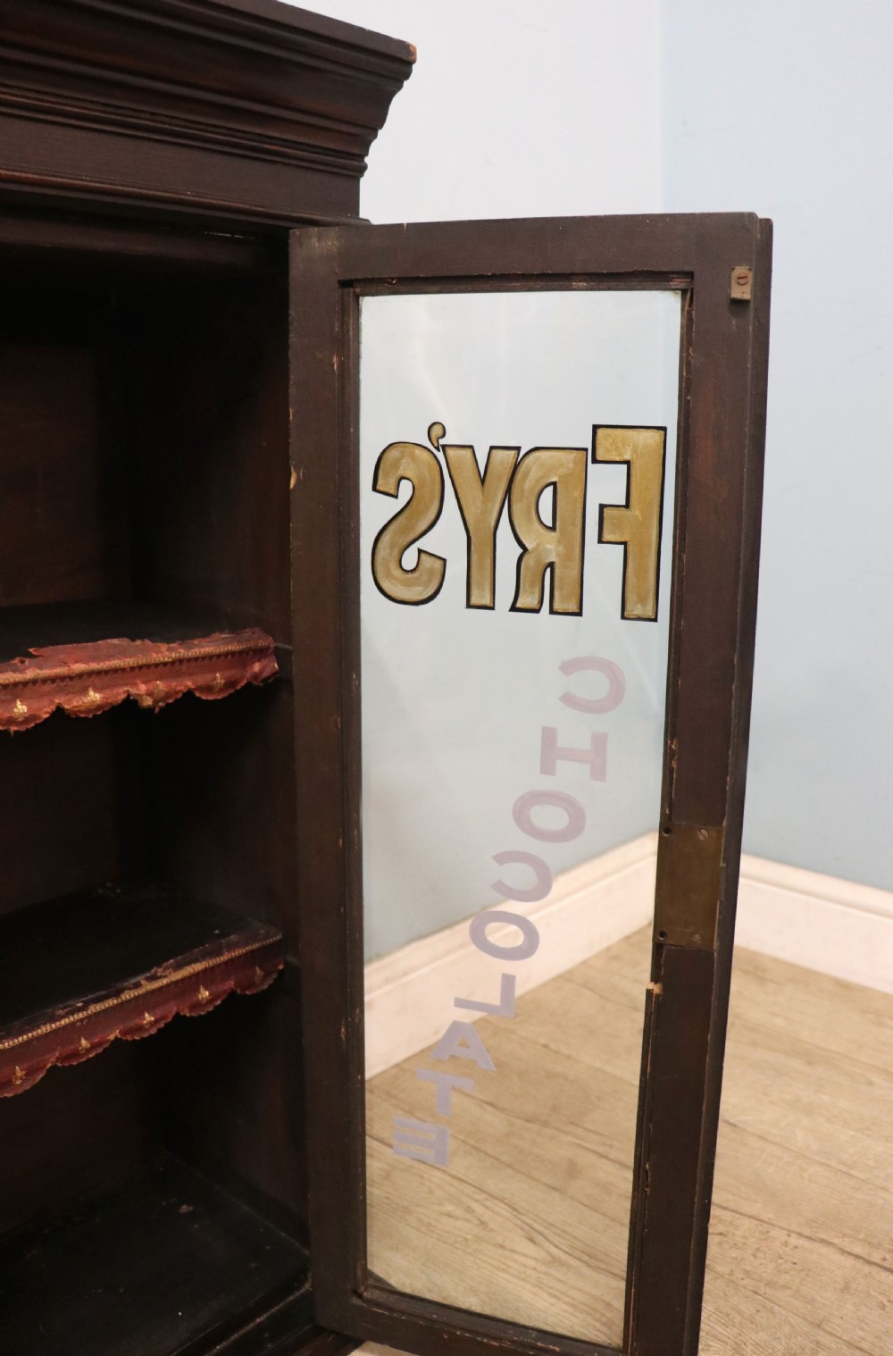 A dark mahogany Victorian display cabinet featuring glazed doors painted with Frys Cocoa and Chocolate advertising typography. View IX