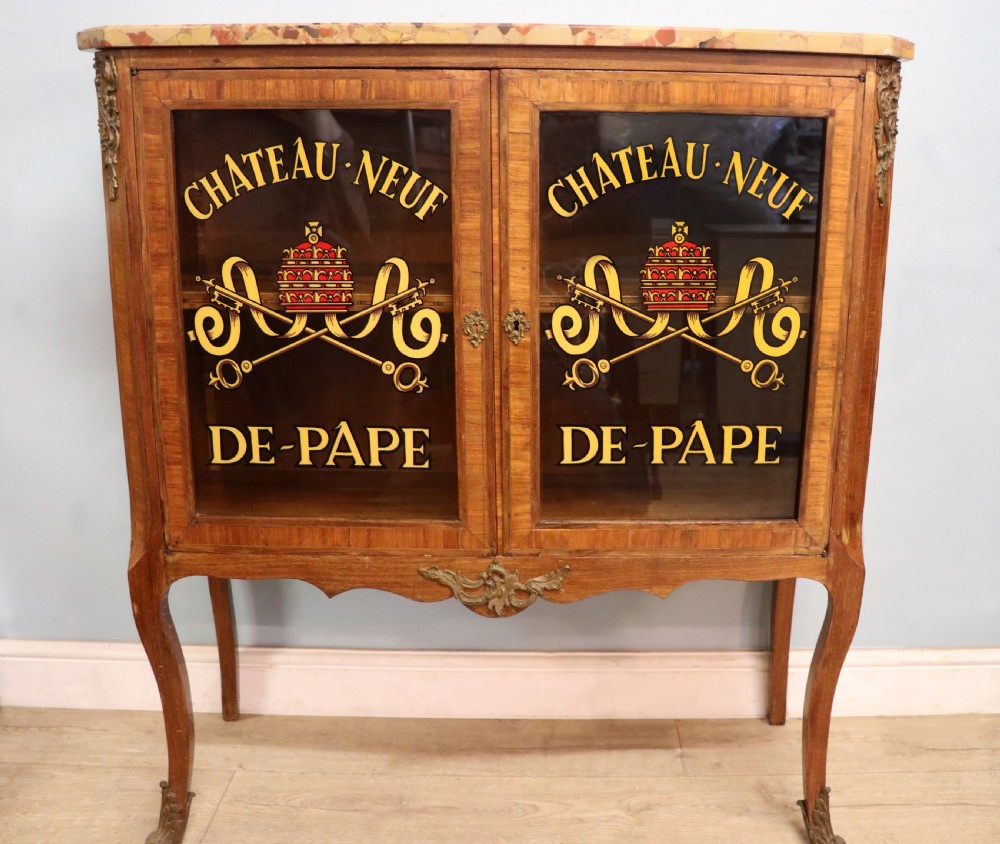 An early 20th-century French wooden display cabinet featuring a marble top, cabriole legs, gilt bronze mounts, and glass doors with hand-painted Chateauneuf-du-Pape lettering.