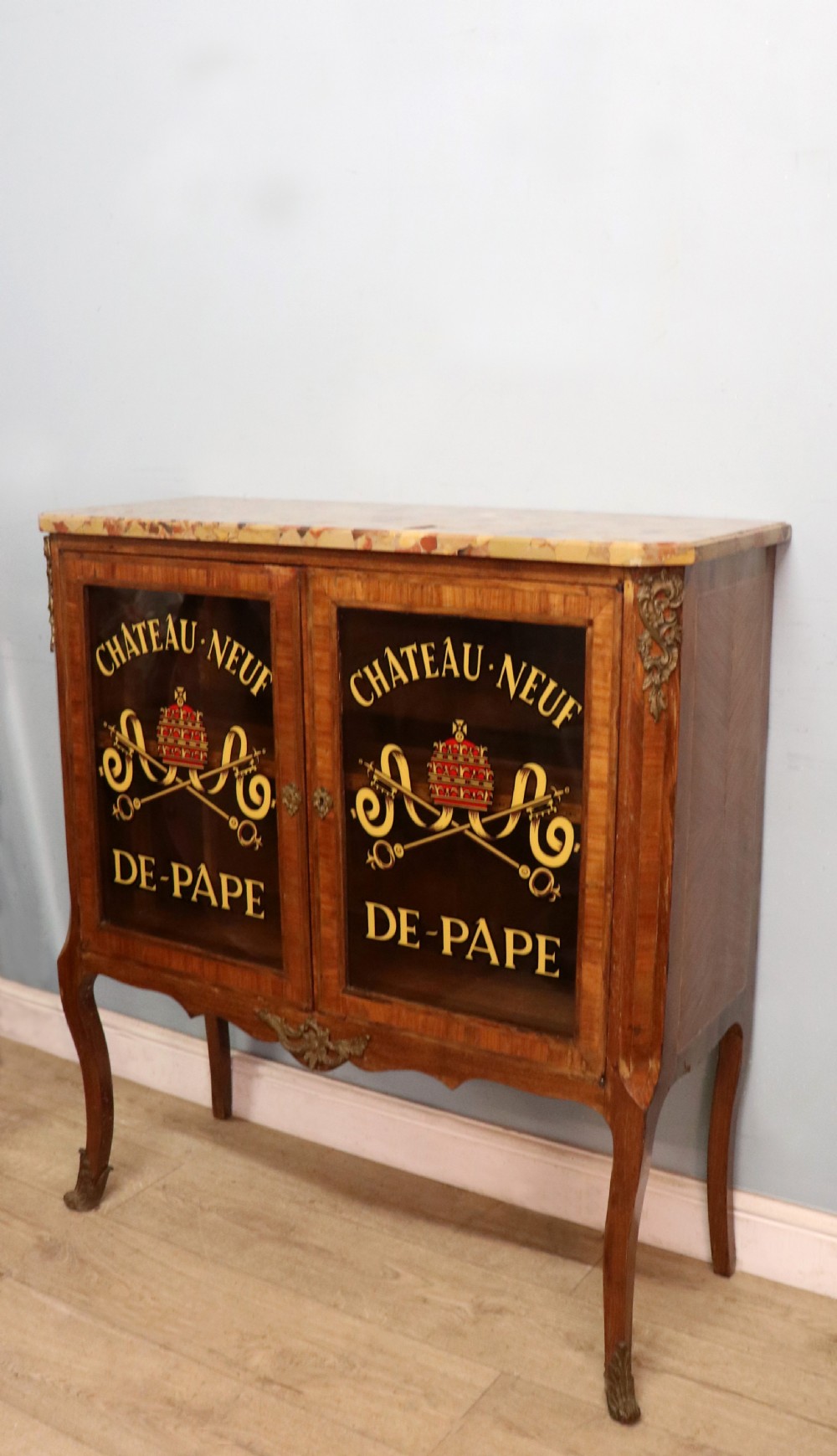 An early 20th-century French wooden display cabinet featuring a marble top, cabriole legs, gilt bronze mounts, and glass doors with hand-painted Chateauneuf-du-Pape lettering. View III