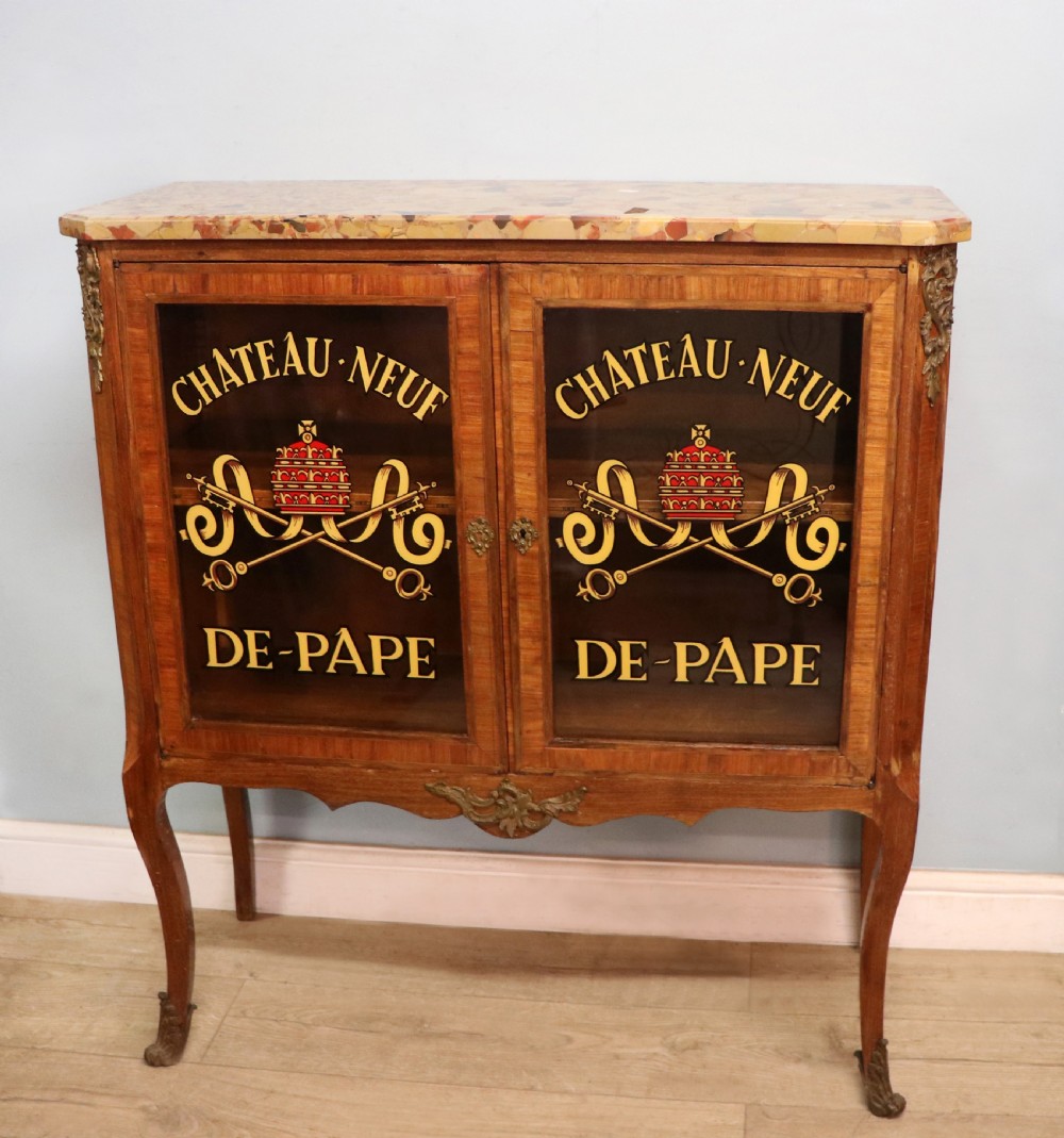 An early 20th-century French wooden display cabinet featuring a marble top, cabriole legs, gilt bronze mounts, and glass doors with hand-painted Chateauneuf-du-Pape lettering. View VII