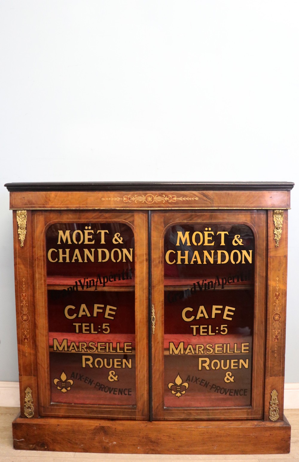 A Victorian walnut veneered and inlaid pier type display cabinet, with advertising for champagne producers Moet & Chandon.