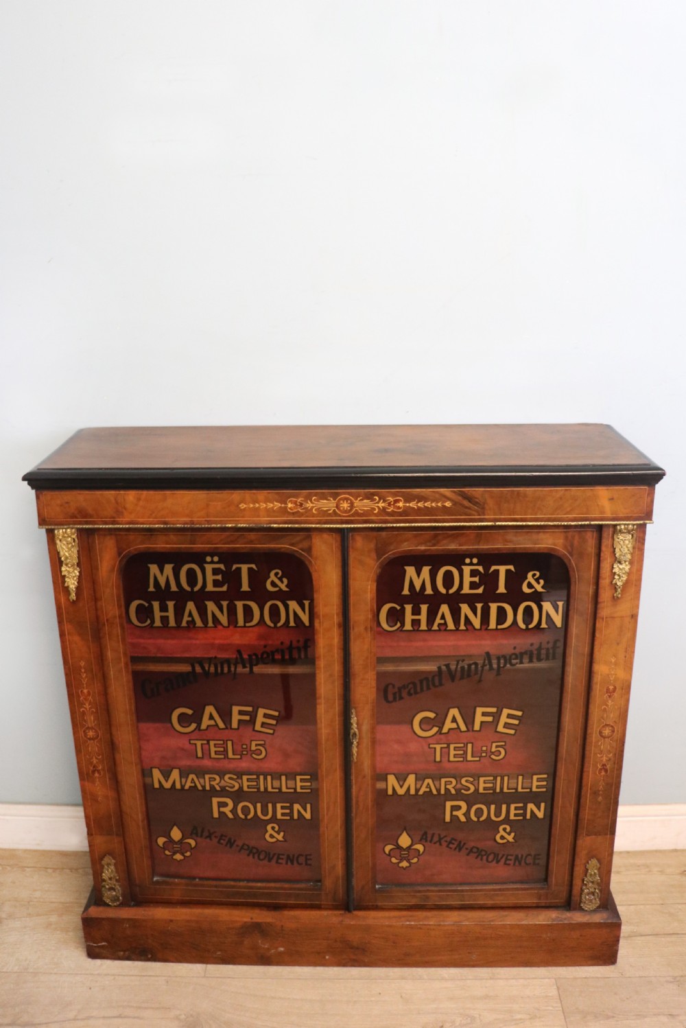 A Victorian walnut veneered and inlaid pier type display cabinet, with advertising for champagne producers Moet & Chandon. View II