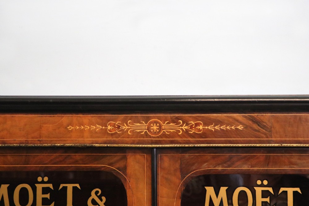 A Victorian walnut veneered and inlaid pier type display cabinet, with advertising for champagne producers Moet & Chandon. View VI