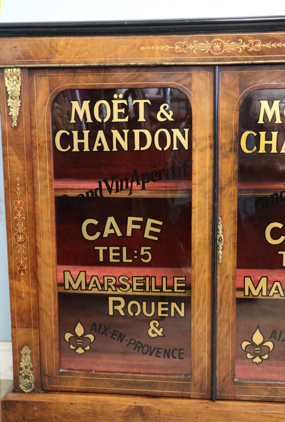 A Victorian walnut veneered and inlaid pier type display cabinet, with advertising for champagne producers Moet & Chandon. View X