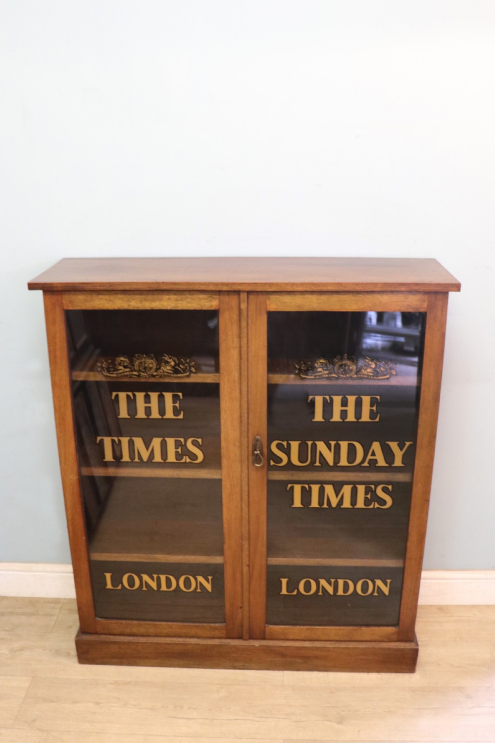 A wonderful late 19th display cabinet with sliding glass doors, later hand sign written for the Times and the Sunday Times. View II