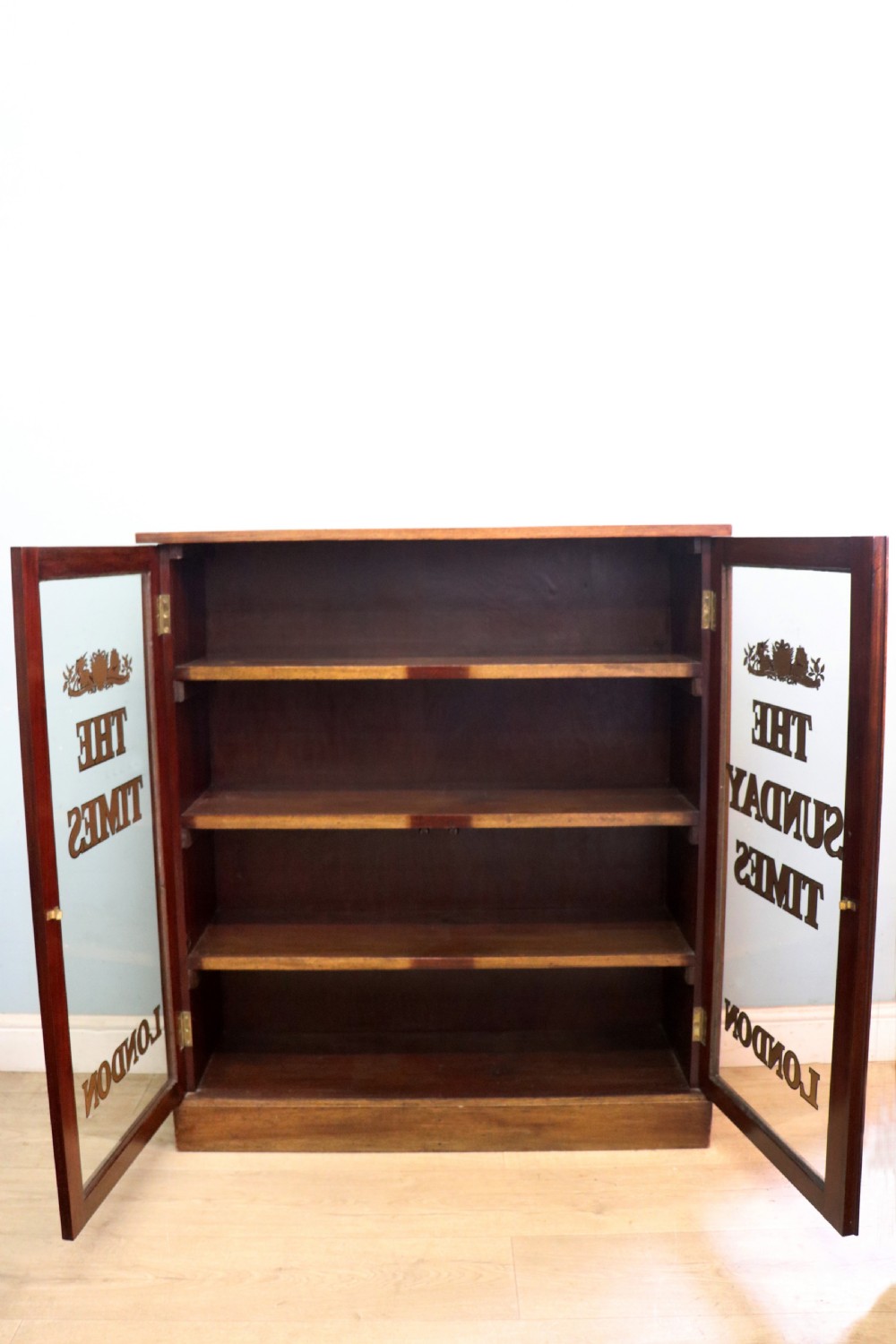 A wonderful late 19th display cabinet with sliding glass doors, later hand sign written for the Times and the Sunday Times. View IV