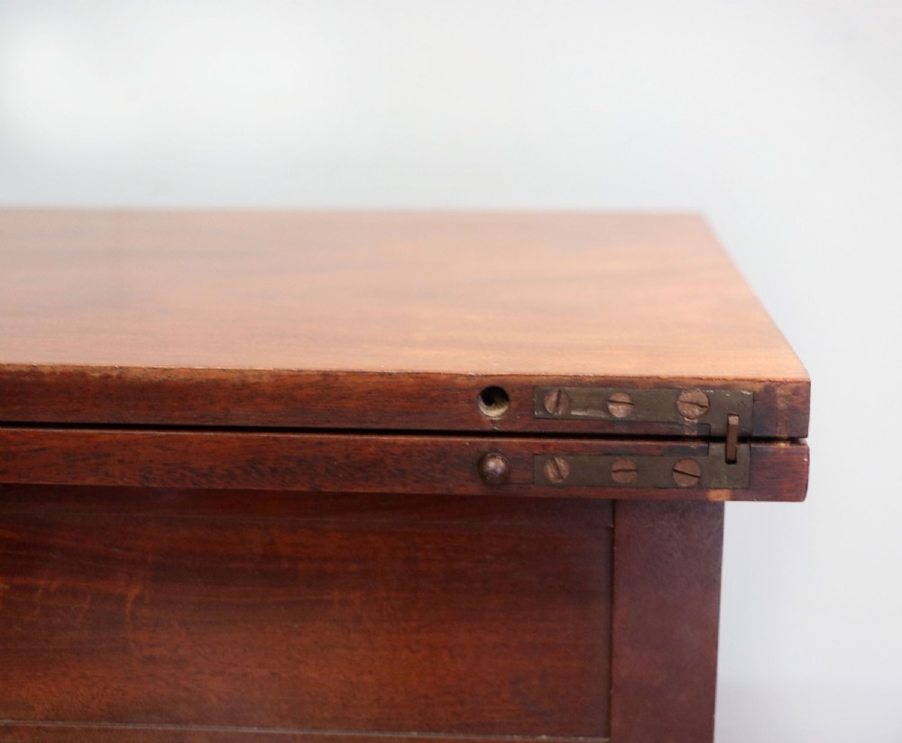 A nineteenth-century Victorian mahogany metamorphic sewing table featuring a hinged top, single drawer with brass escutcheon, tapered wooden storage bin, carved side supports, and brass castors. View XXIV