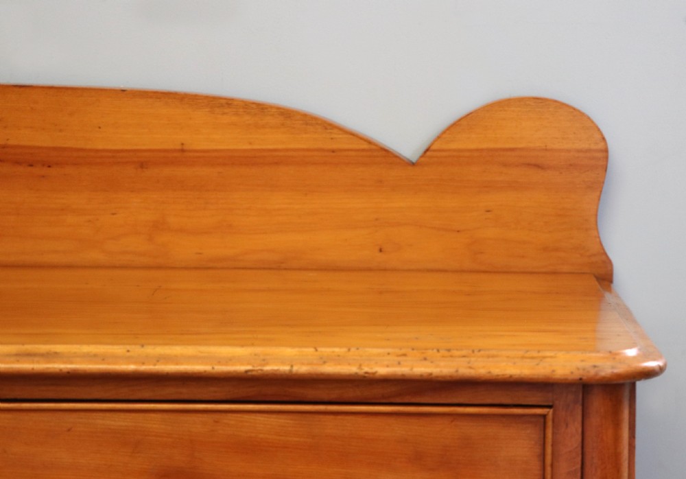 A Victorian satin birch chest of drawers featuring a shaped gallery backboard, two short over two long drawers with turned knobs, resting on a plinth base. View XI