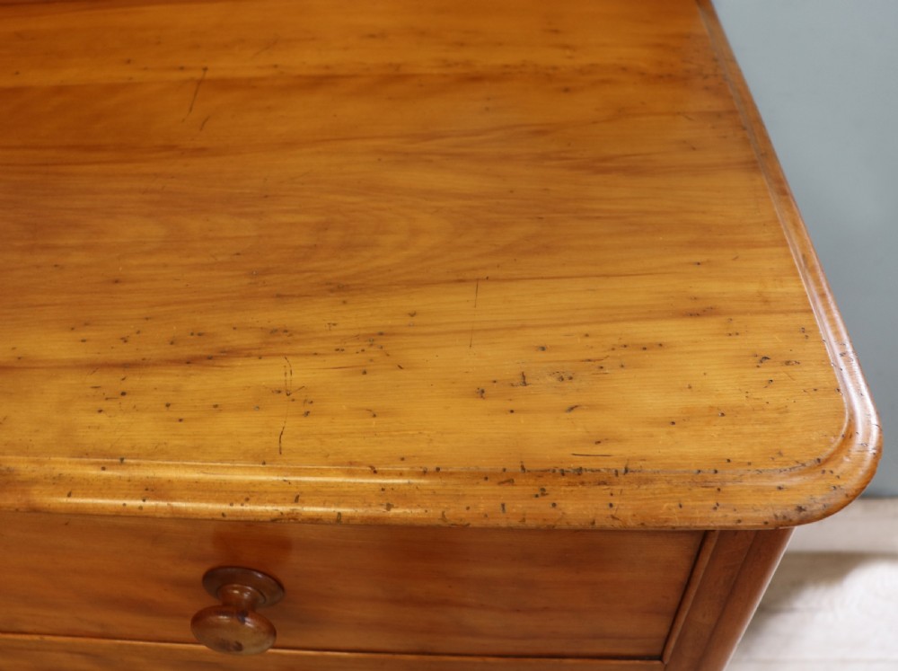 A Victorian satin birch chest of drawers featuring a shaped gallery backboard, two short over two long drawers with turned knobs, resting on a plinth base. View XII